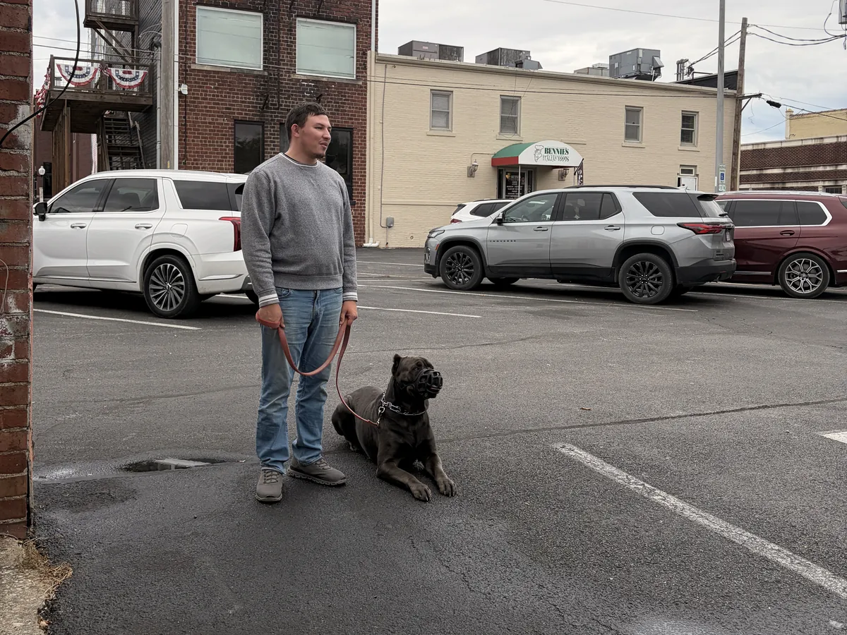 Owner Austin Todd practicing a down-stay with a dog on a leash outside the Rising Sun facility